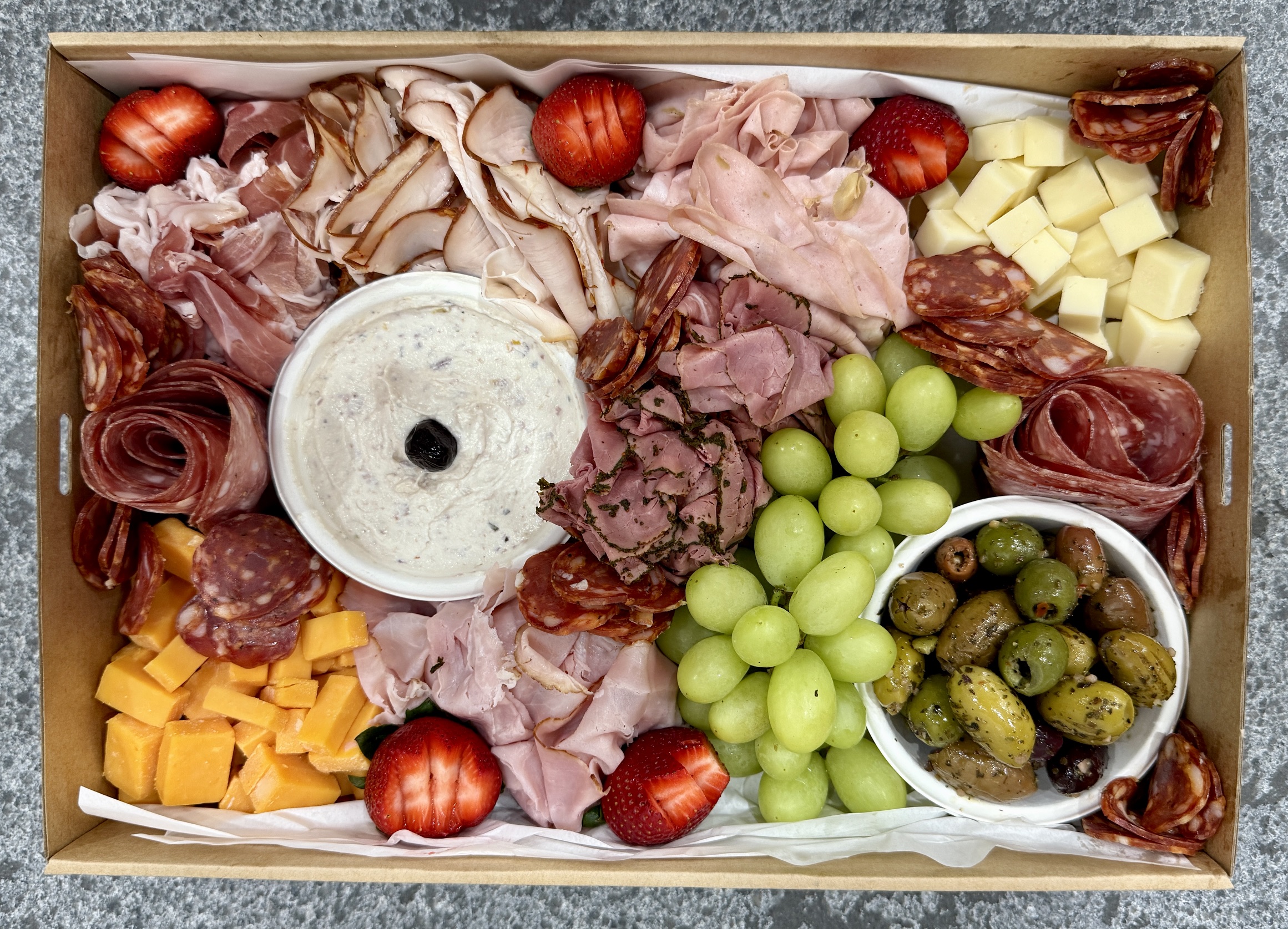 DeliCut platter with sliced meats, cheeses, olives, grapes and dip